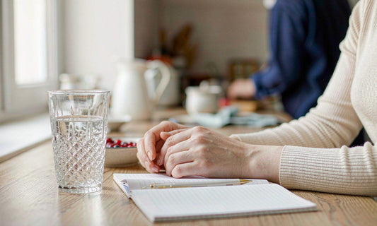 A family habit notebook open on a bright kitchen counter beside a glass of water and berries