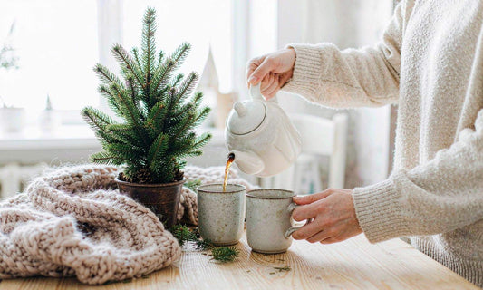 Warm winter family scene: tea poured into two stoneware mugs on a light oak table