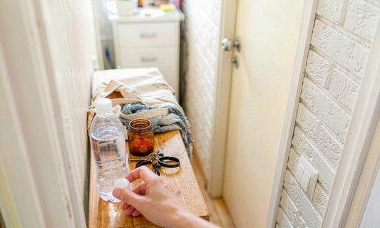 A hallway console by the front door with a gummy jar, water bottle, keys, canvas tote and a scarf