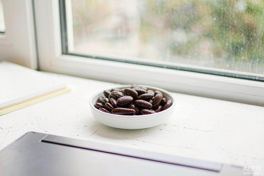 Macro of dark velvet beans in a white ceramic dish on a pale desk beside a laptop edge in soft window light