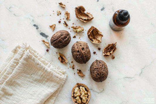 Flat lay of whole and cracked black walnuts with an amber dropper bottle and linen cloth on white marble