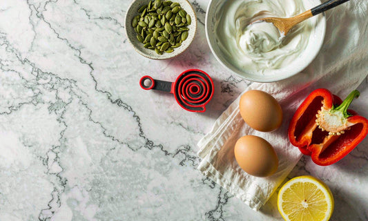 Overhead flat-lay of pumpkin seeds, yogurt, eggs and peppers for a lysine routine