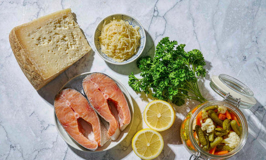 Aged cheese, sauerkraut, fresh fish fillets, lemon and parsley arranged in a row on white marble