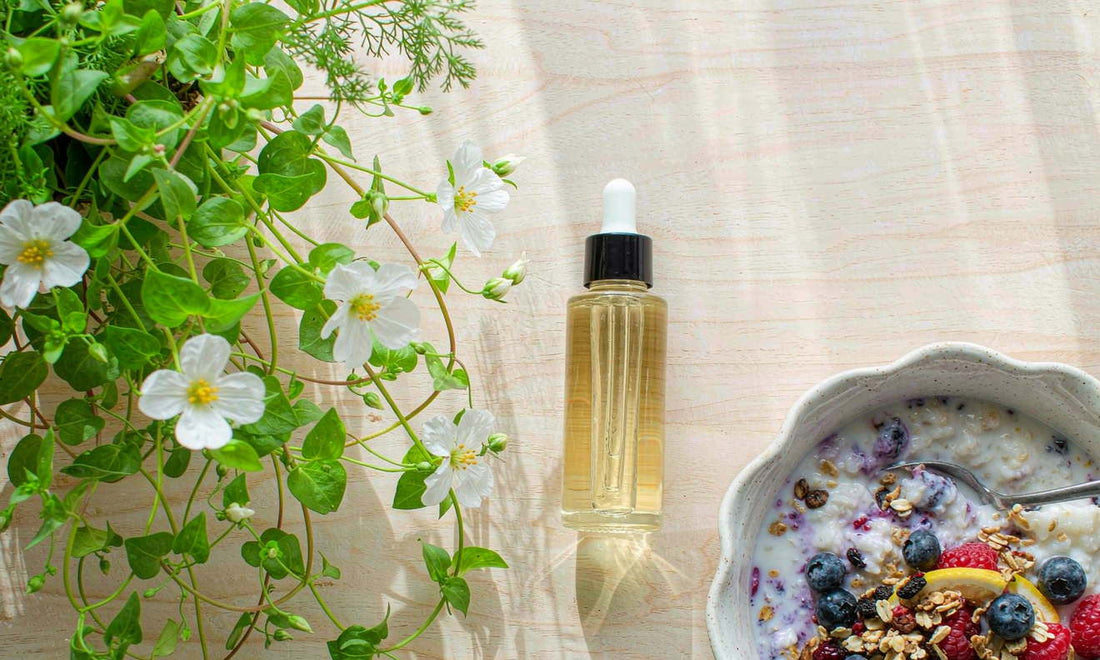 Ingredient flat lay of fresh bacopa leaves, white flowers and a glass dropper bottle beside porridge