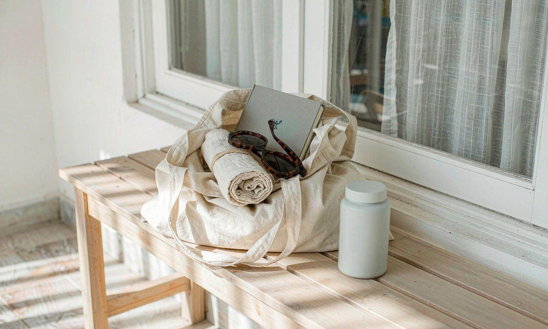 Canvas tote, white supplement bottle and notebook on a light bench by a window
