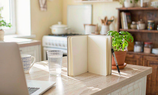 An open family wellness notebook and pen on a light oak kitchen counter in soft morning light