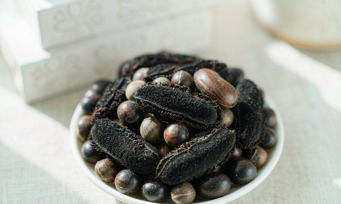Extreme macro of dark velvet beans and pods in a white ceramic dish on pale linen in soft light